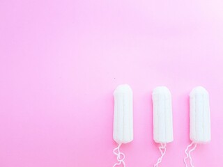 Women's hygiene intimate accessories. A clean white tampon on a pink background. Menstrual cycle. Space for text.