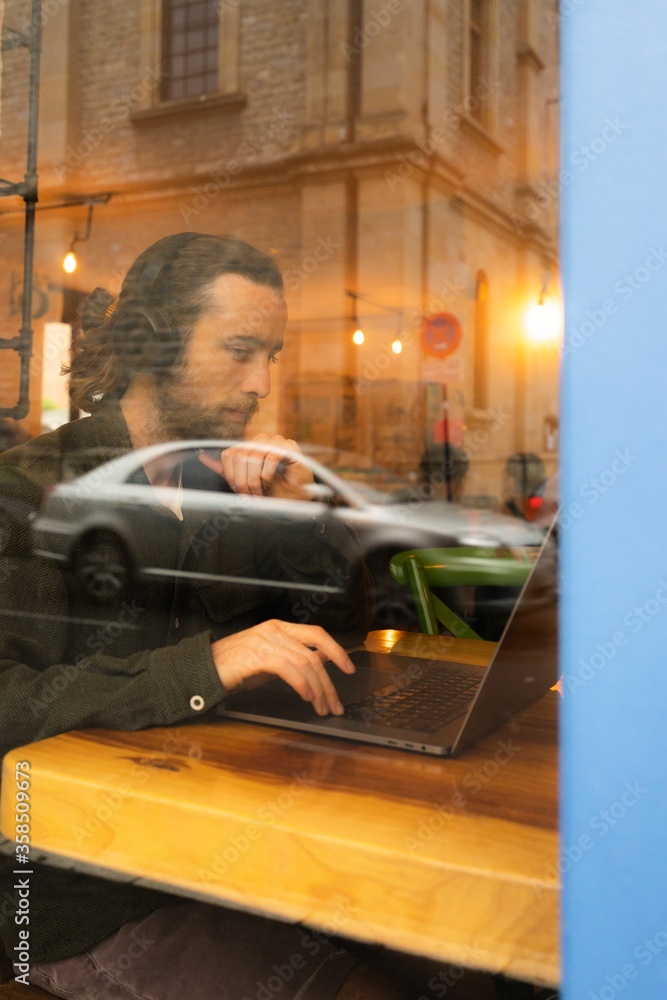 Aufkleber reflection of a man with beard working with headphones and computer