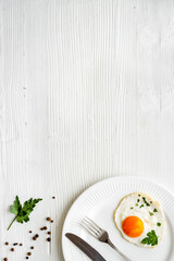 Fried eggs on plate - white wooden dinner table from above copy space