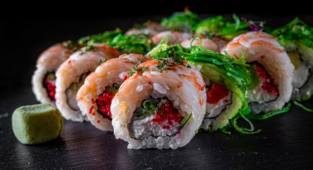 set of Sushi rolls with seafood, srimp, cream cheese,caviar and Chuka salad on black wooden table background
