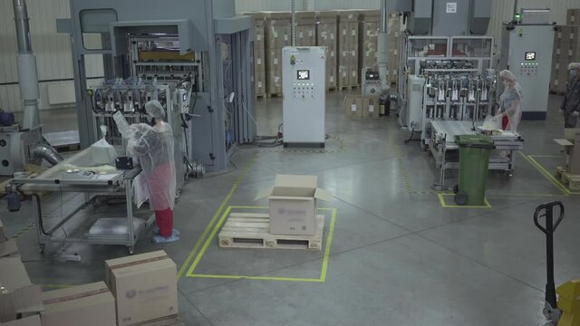 Caucasian Women Packing Food Dish Containers On Production Site. Wide Shot Of Factory Workers Working On Plant Manufacturing Conveyor. Business, Production, Industry.