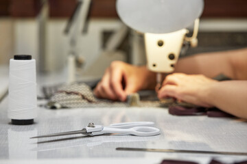 Fototapeta premium girl seamstress sew on the sewing machine. Women's hands sewing on the sewing machine. Tailoring process
