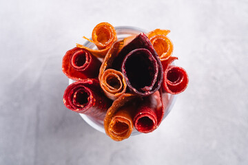 Fruit pastille in glass cup on stone concrete background. Organic sugar free roll up food made from...