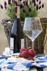 Relaksowy połudzień. Wino z winogron, sera i pistacji. Na tle wazon z lawęndą.