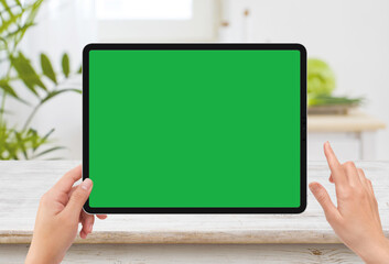 human left hand holding black tablet media device with white green screen mockup