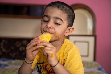 Happy little boy eating mango (lockdown activities)