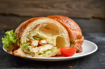 Croissant sandwich with chicken breast and lettuce. Croissant sandwich cut in half. Delicious nutritious breakfast. Free space for text.