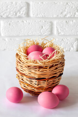 Easter composition with wicker basket and pink colored eggs