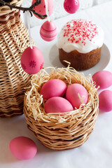Obraz na płótnie Canvas Easter composition with pink colored eggs in wicker basket and Easter cake
