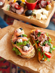 bruschettas with roast beef and salmon on parchment and wooden board