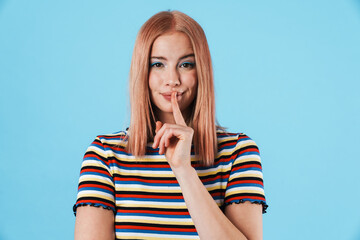Image of beautiful pleased woman showing silence gesture at camera