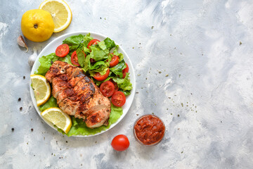 Grilled chicken breast salad with spinach and tomatoes. Healthy eating Fried chicken breast, lemon, cherry tomatoes, spinach and lettuce. Light background. Top view