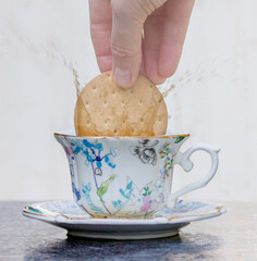 Dunking a biscuit in a cup of tea, with the resulting tea splashing out.