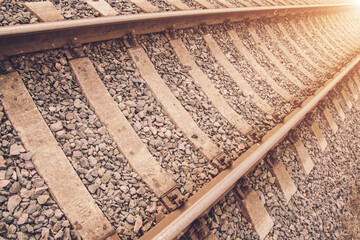 Naklejka premium vintage railway site with old rails and sleepers against bright sunlight