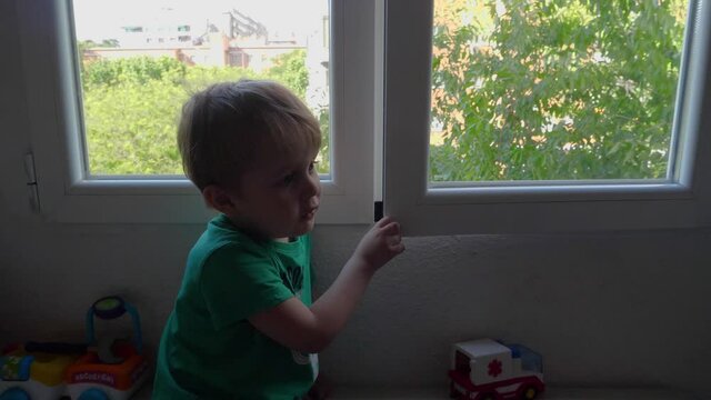 lovely blond boy playing with a window