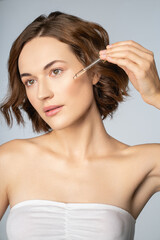 Naklejka premium Young pretty woman using serun for face