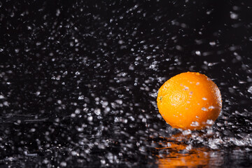 Fototapeta na wymiar Orange in water splash on black background