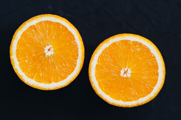 Top view on orange slices on black background.