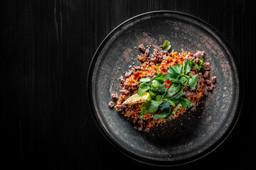Fried rice with beef meat and vegetables in plate on black wooden table background