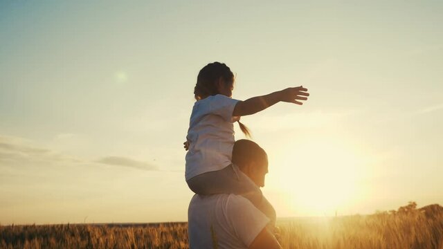 happy family silhouette teamwork concept slow motion video. daughter little girl sitting on his father man lifestyle neck depicts a flight of an airplane playing a pilot. parent dad and child kid