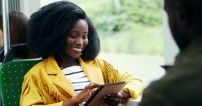 Portrait of smiling african american girl with an afro hairstyle  using tablet in public transport.