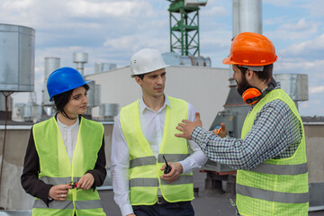 Good looking multiethnic group of workers in a modern building construction site analyzing the plan...