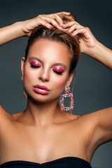 Beautiful young woman with evening make-up in luxury jewelry with pink diamonds. Glossy lips and eyeshadow. Smooth hair.