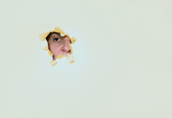 A woman looks through a hole in the paper wall 