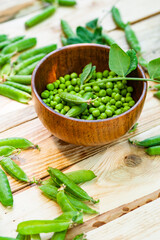 closeup green peas in brown dish, on wooden table.