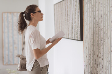 Woman standing in the art gallery and looking at the paintings