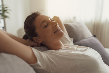 Happy woman lying on the sofa at home and relaxing