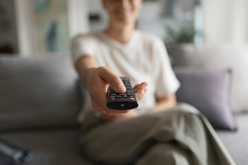 Woman watching TV and holding the remote control