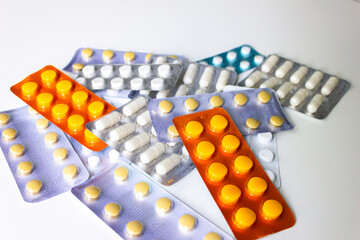 A lot of packs of white, orange and blue pills lie on the table