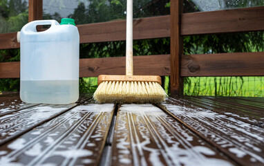 Brush and plastic canister with detergent on a wooden board, wooden terrace. Technologies and tools...