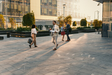 Group of business people walking outside in front of office buildings.