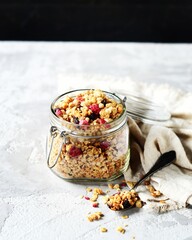 Homemade granola with berries and nuts in a bowl on a gray background