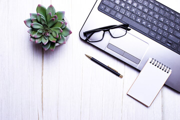 On a light background are a pen, computer, glasses, flower, notebook. Place to insert text. Close...