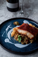 Fine dining restaurant: grilled cod with crust, capers and couscous on grey concrete table