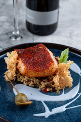 Fine dining restaurant: golden cod fillet with couscous and rice chips, garnished with unusual blue sauce