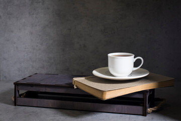 Small white mug on a pile of notebooks.