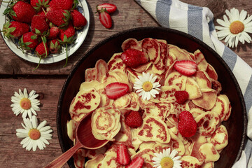 Obraz na płótnie Canvas Pancake cereal with strawberries. Mini pancakes in a pan. Strawberry pastries