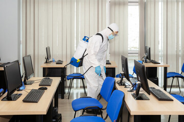 People in virus protective suits and mask disinfecting buildings of coronavirus with the sprayer