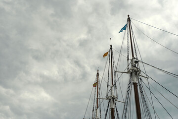 Tall elegant lines of ship masts against grey stormy skyline outside. Barcelona, Spain 