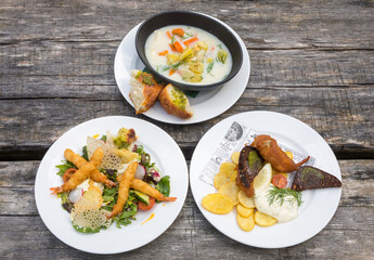 Set of  seafood dishes with touch modern cuisine  - prawn salad, fish soup, fish and chips on the coastal  restaurant outdoor table