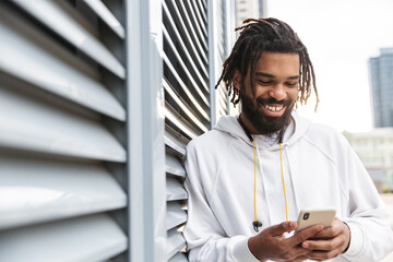 Cheery young man using mobile phone