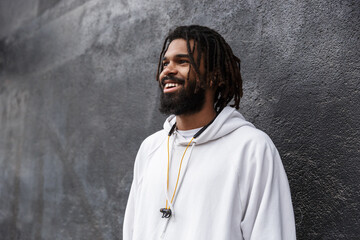 Young man walking outdoors with earphones on neck