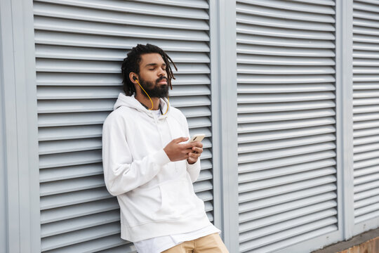 Man with earphones using mobile phone - Powered by Adobe