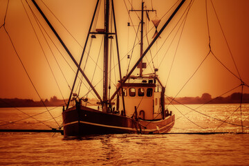 Silhouette vom Fischerboot bei orangefarbenem Licht