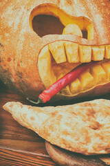 Hungry pumpkin with pepper. In mouth a pointy red pepper tongue sticks out between crooked tip...