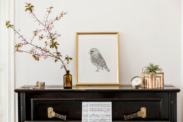 Elegant composition at living room interior with black piano, gold mock up poster frame, spring flowers, decoration, clock and stylish presonal accessories in modern home decor.